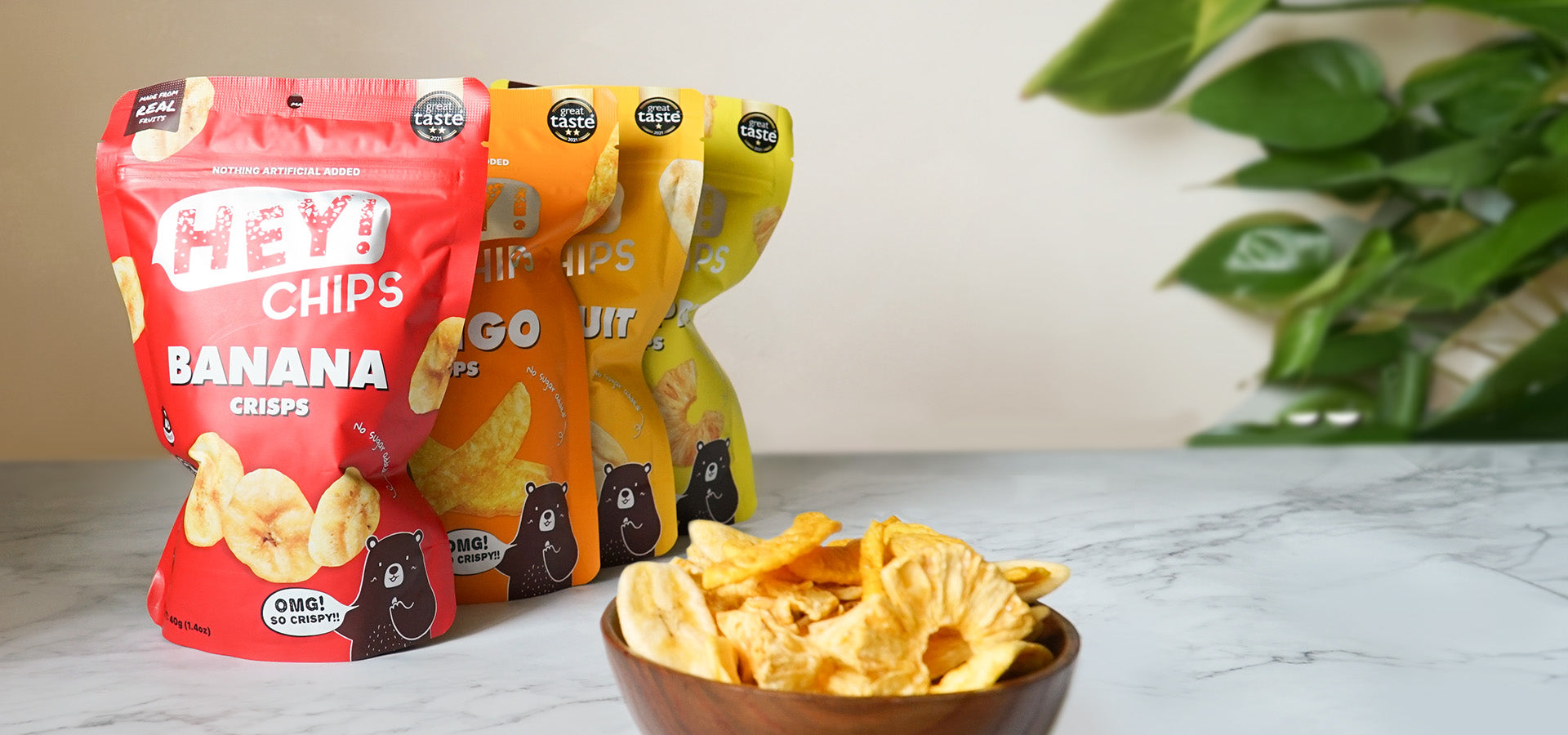 Hey! Chips signature collection including banana, mango, jackfruit, and pineapple crisps shown in a bowl on a table.