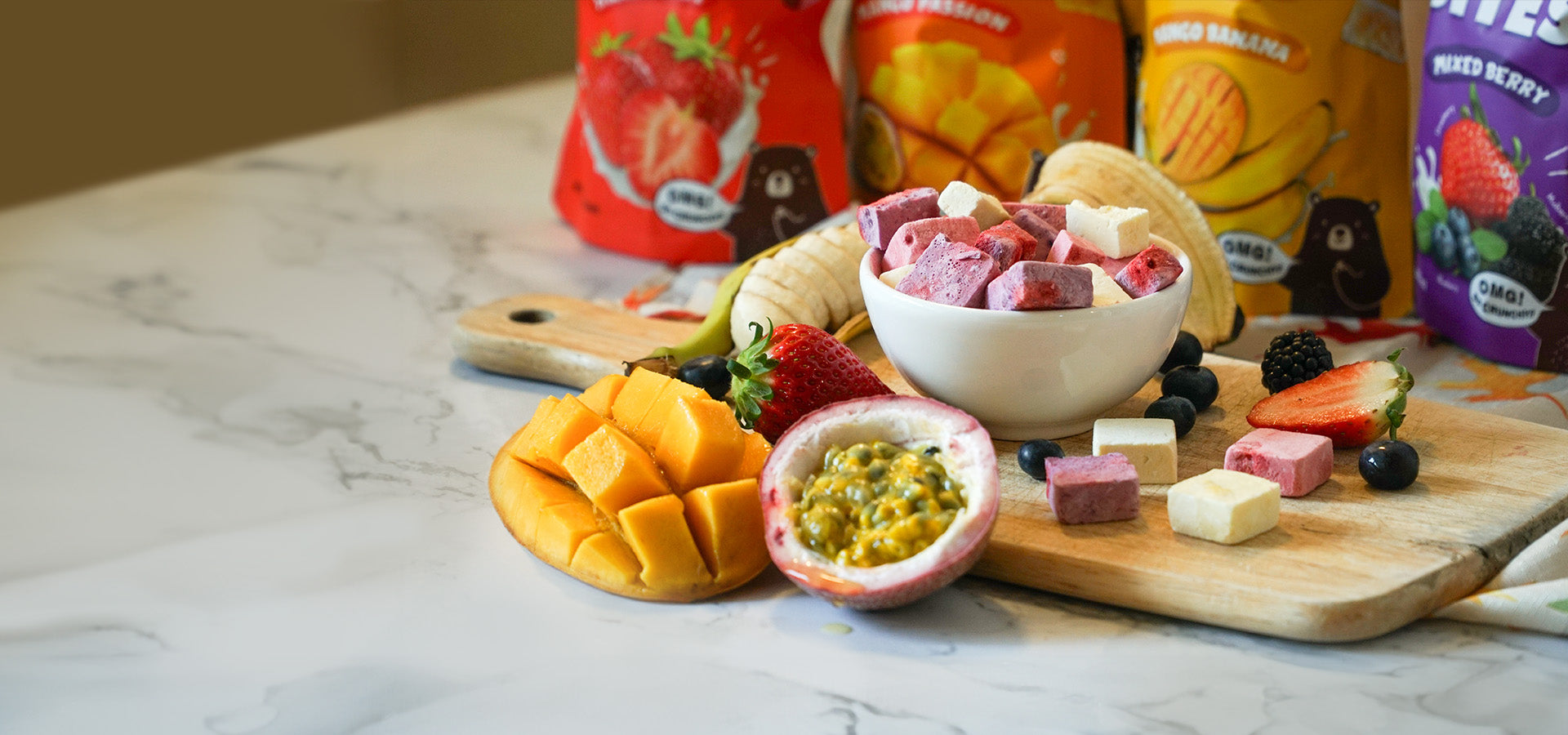 Hey! Chips fruit bites with real mango, strawberry, and blueberry, with packs of Hey! Chips in the background.