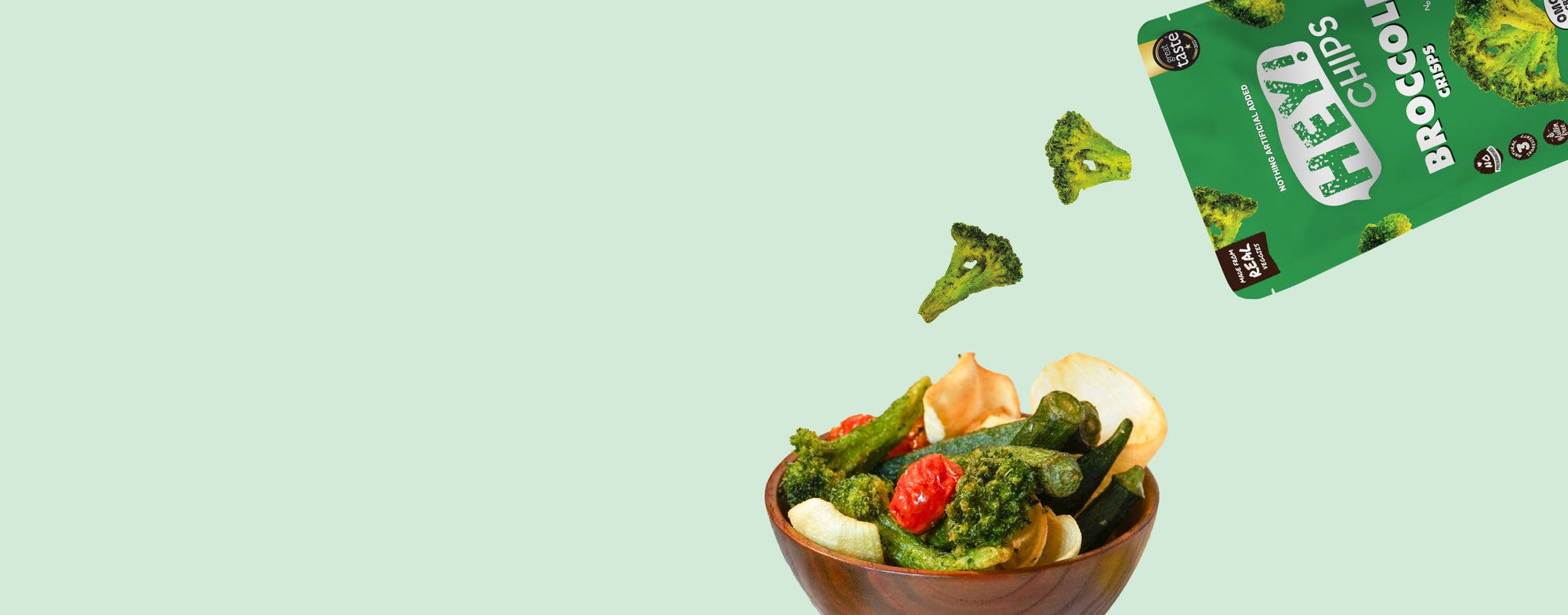 Mix of Hey! Chips products including okra crisps and broccoli crisps being poured out into a wooden bowl.