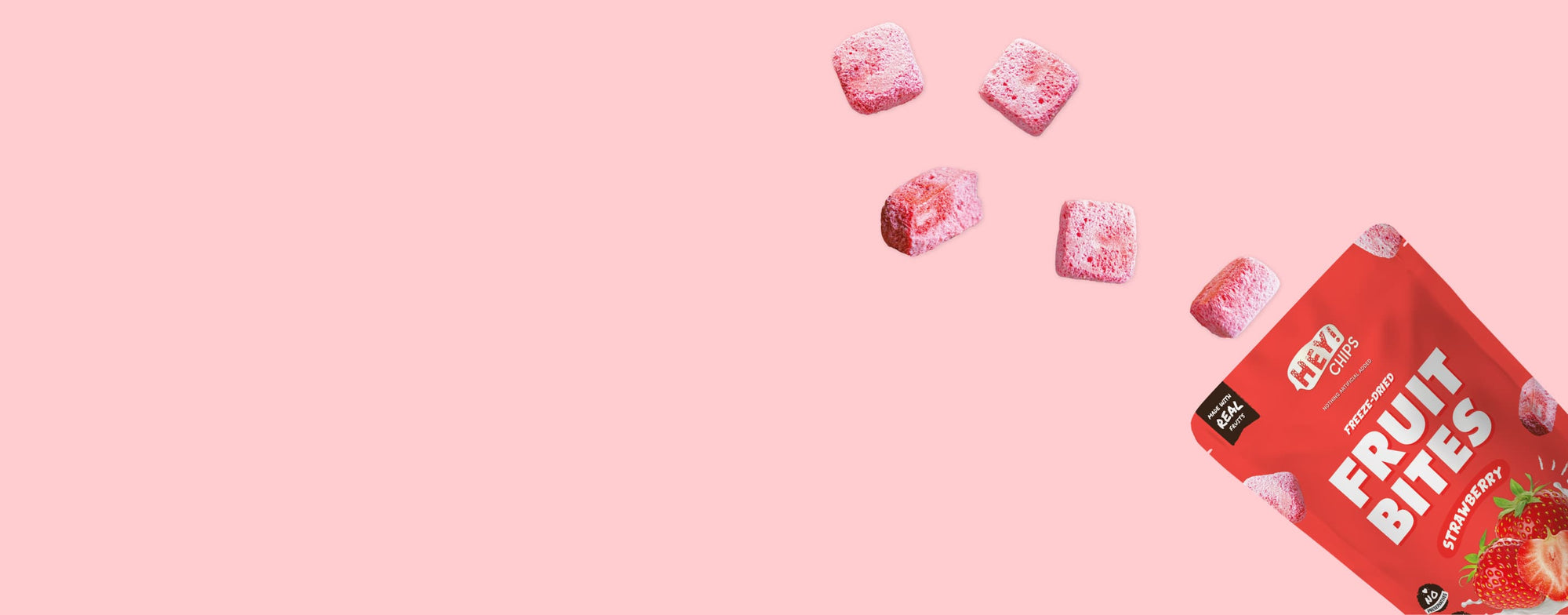 Hey! Chips strawberry fruit bites being poured out with actual freeze-dried strawberry crisps on a pink background.