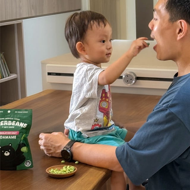 Man and child sitting at a table with a package of Superbeans and a bowl of superbeans.
